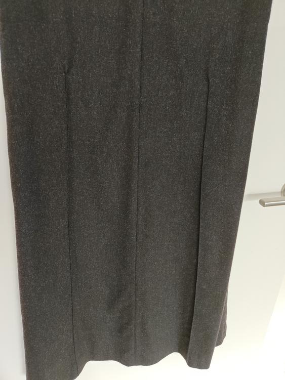 Dark grey long skirt hanging on a white door, showing fabric texture and vertical seams.