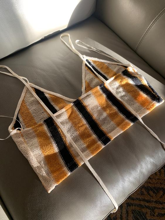 Black, white, and gold striped knit camisole top on a gray sofa, lit by natural light.
