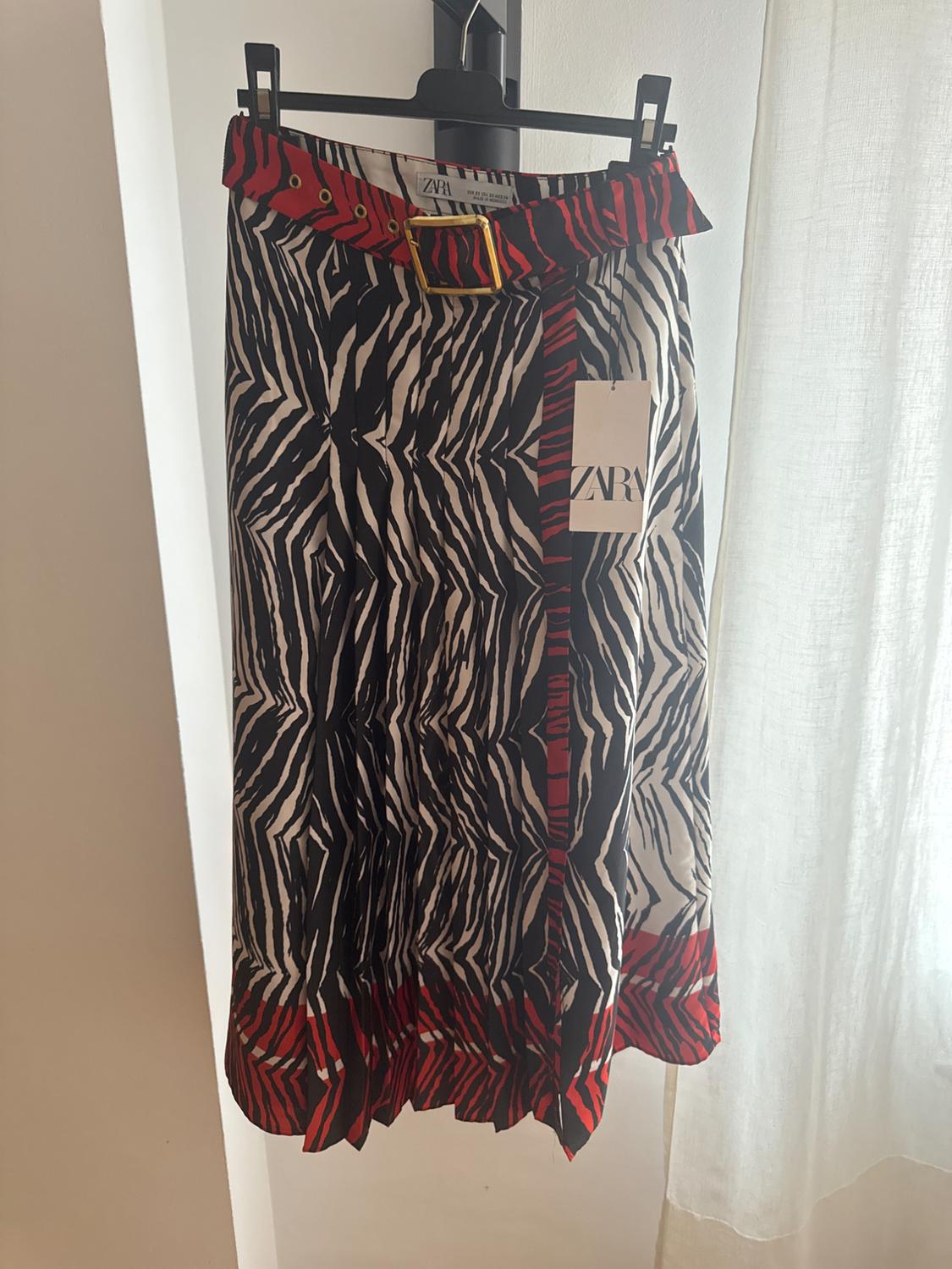 Hanging skirt with black and white zebra print, red detailing and belt with gold buckle. Visible label with text "ZARA".