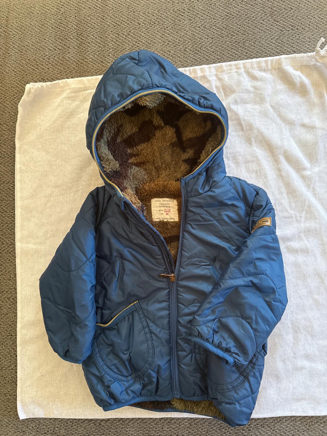 Blue jacket with hood and brown plush lining, on white fabric. Visible label inside.