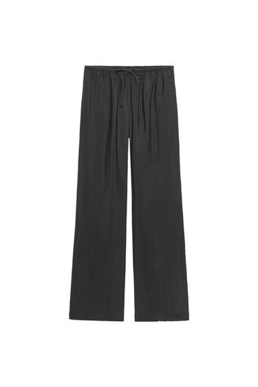 Front view of black wide-leg trousers with elasticated waistband and adjustable drawstring.