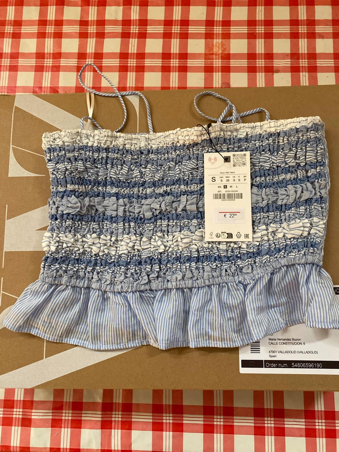 Blue and white striped gathered top on box and tablecloth. Text: S, €22.95, Maria Hernandez Buzon, Order no. 54806596190.