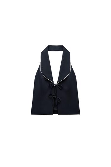 Front view of a black vest with a wide neck and ties in the front.