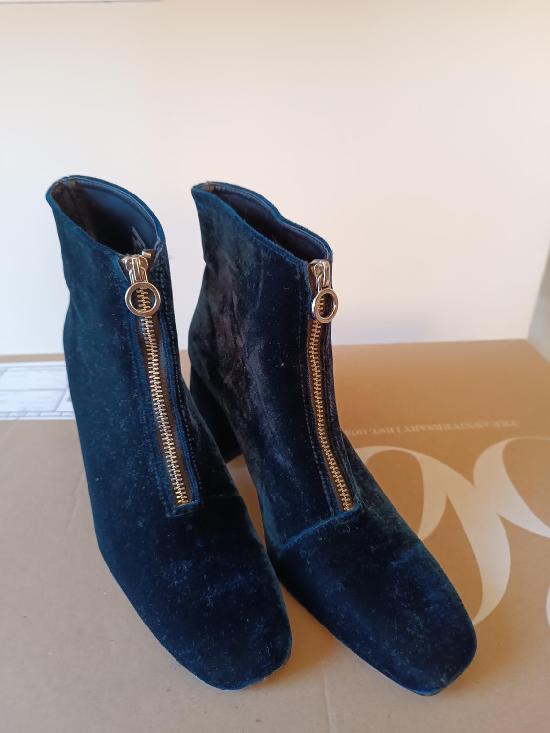Dark blue velvet ankle boots with gold zips at the front, on a cardboard box with partially visible text.