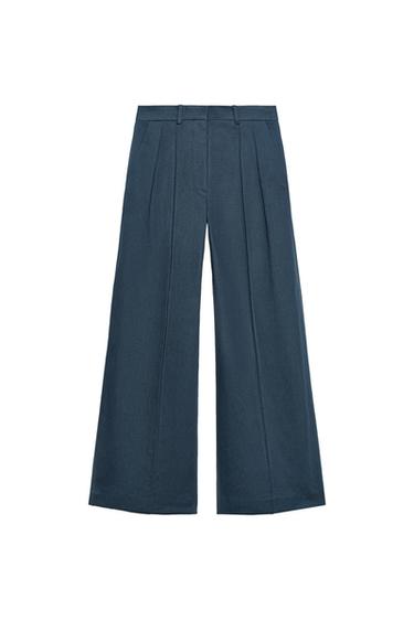 Front view of navy trousers with pleats, wide leg and waistband with belt loops.