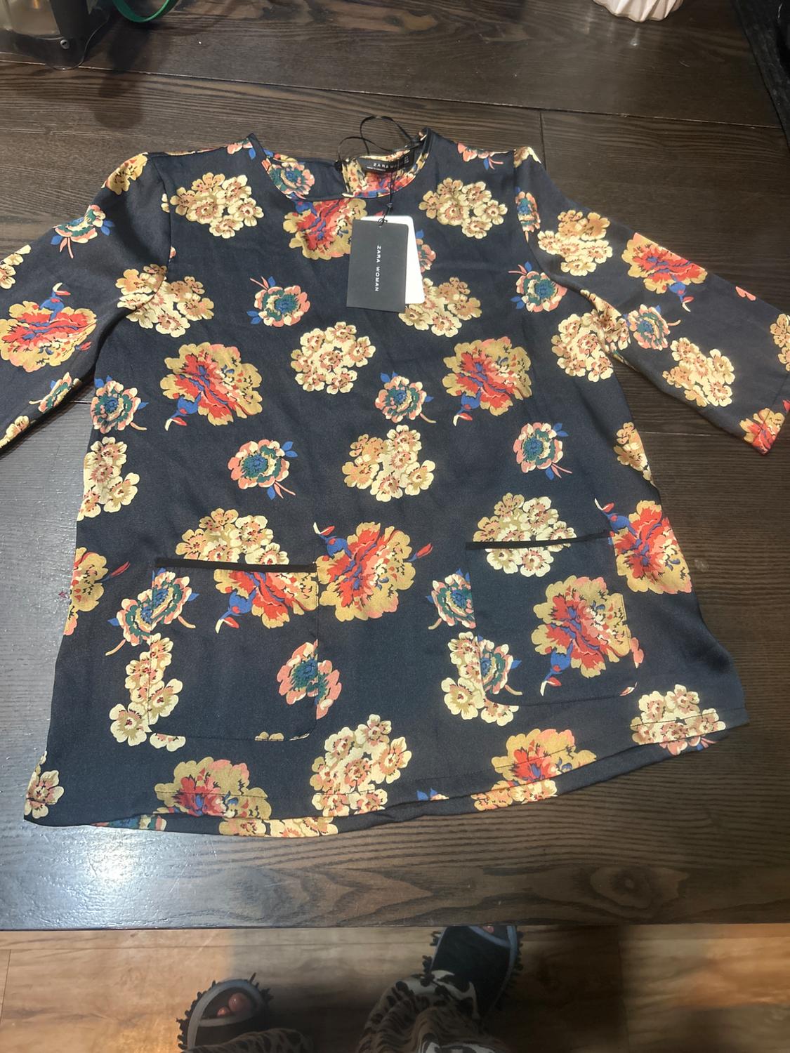 Front view of floral dress with front pockets and hang tag.