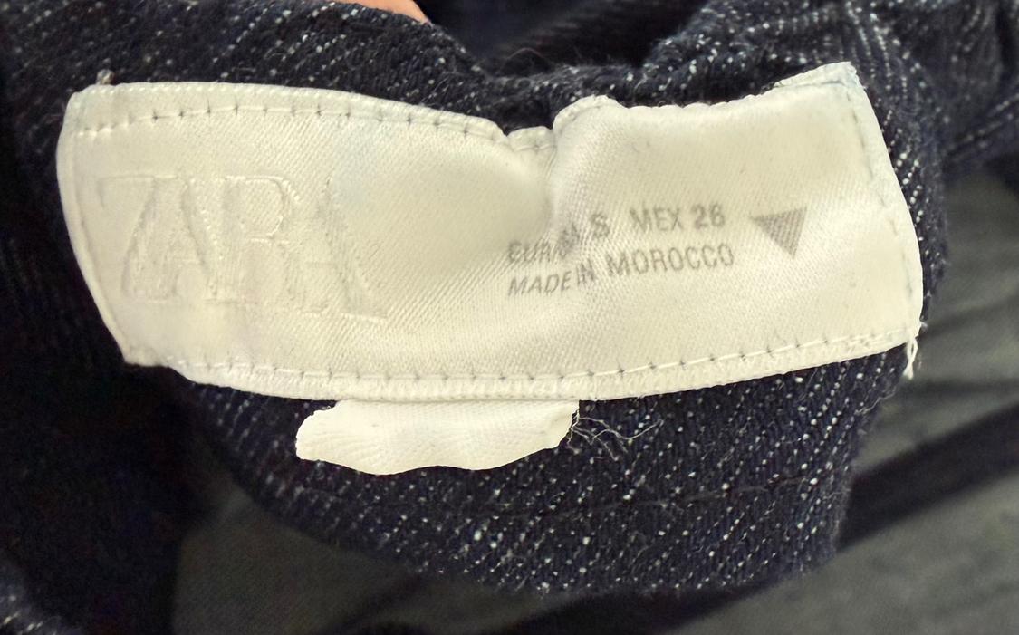 Clothing label with the text "ZARA", "EUR S MEX 28", "MADE IN MOROCCO" on dark, textured fabric.