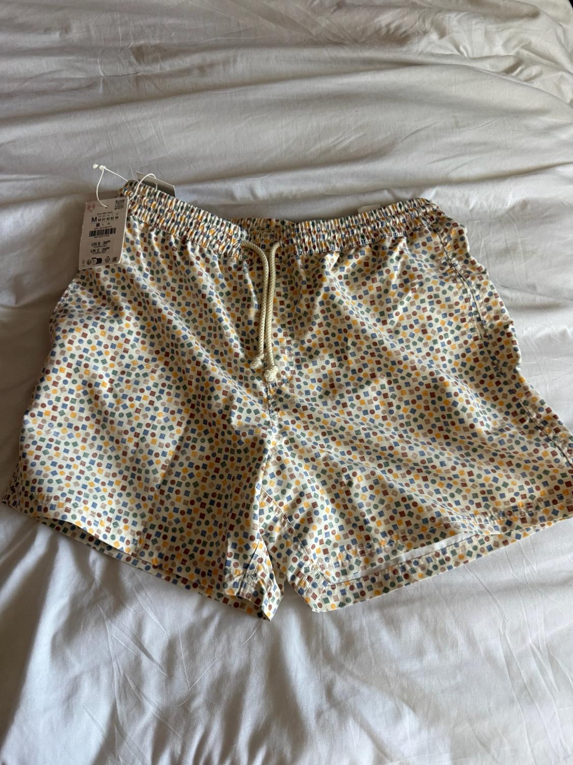 Multicolored geometric-print shorts with an elastic waistband and drawstring, on a white sheet.