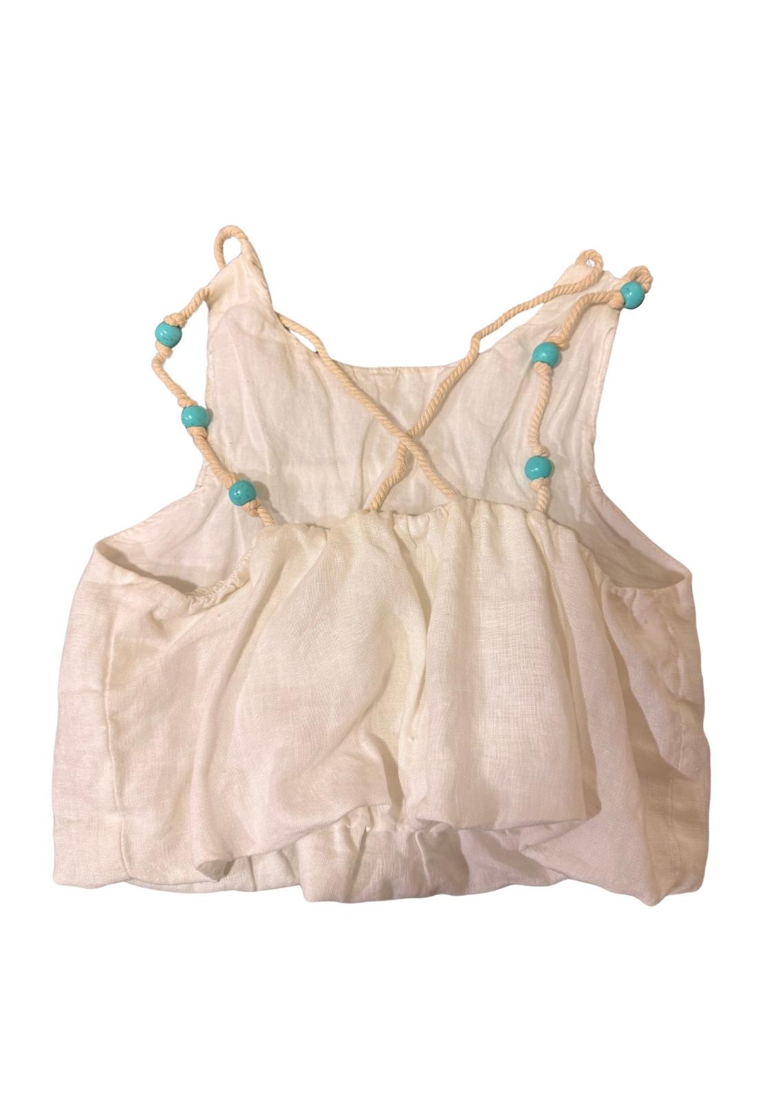 White strappy blouse with turquoise beads and a criss-cross back design, on a white background.