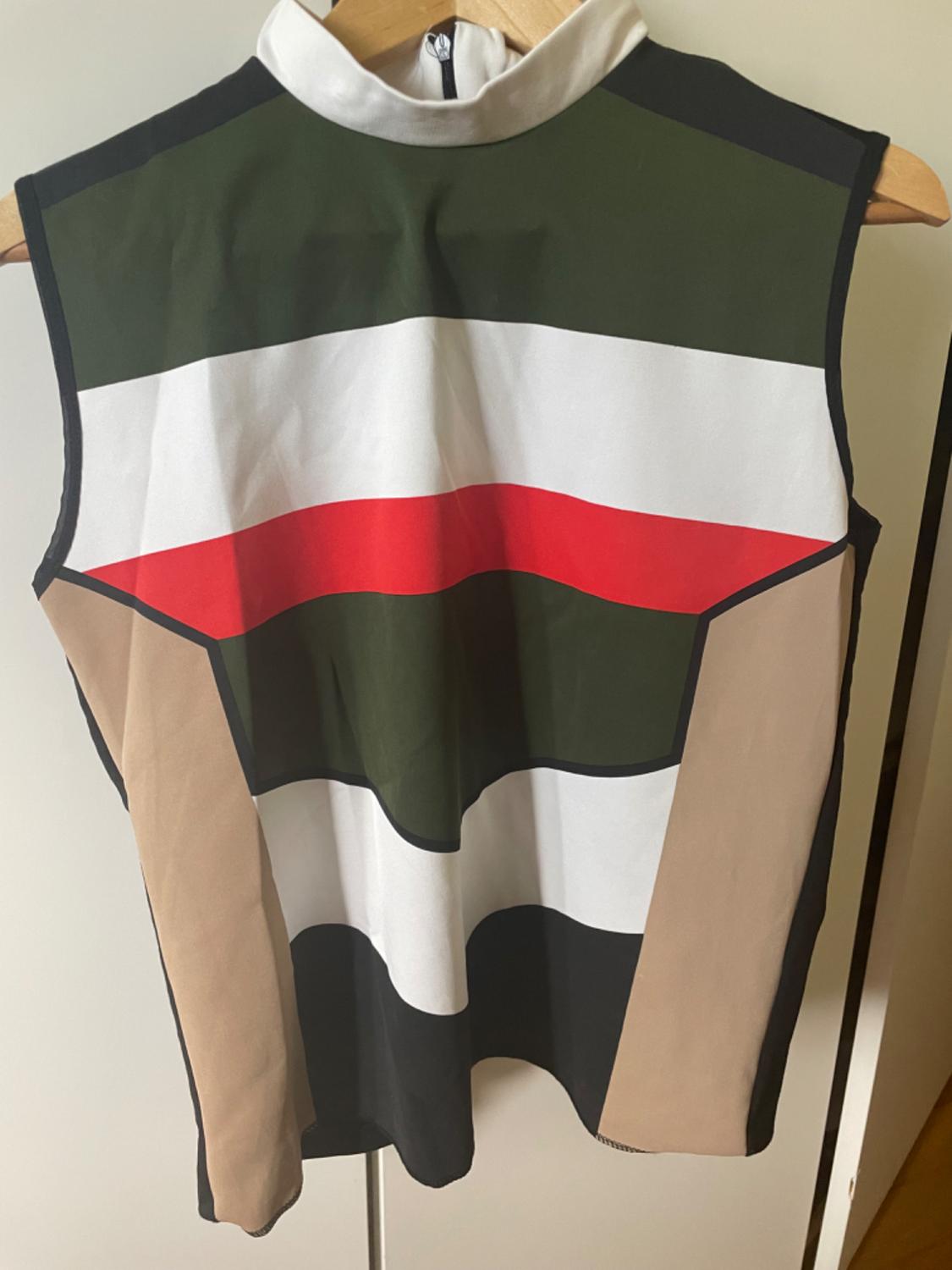 Front view of a sleeveless blouse with a stripe print in green, white, red, beige, and black, high neck.