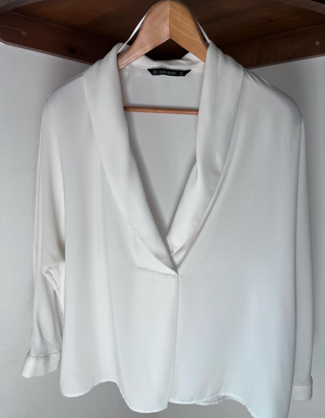 Front view of a white blouse with a lapel collar and long sleeves.