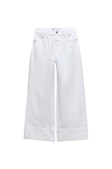 Front view of wide-leg white trousers with side pockets and a front button.