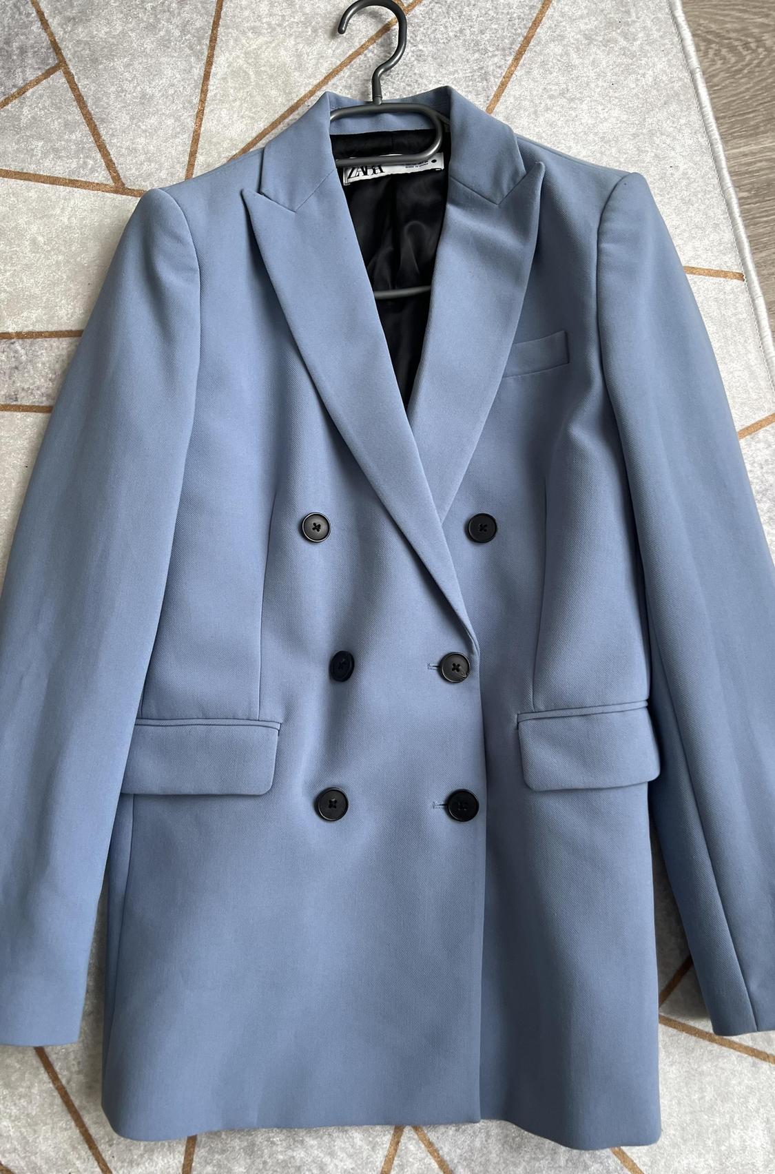 Front view of blue blazer with black buttons and side pockets.