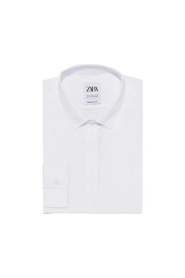 Front view of a folded white shirt with a classic collar and the text 'ZARA SUPERSLIM FIT'.