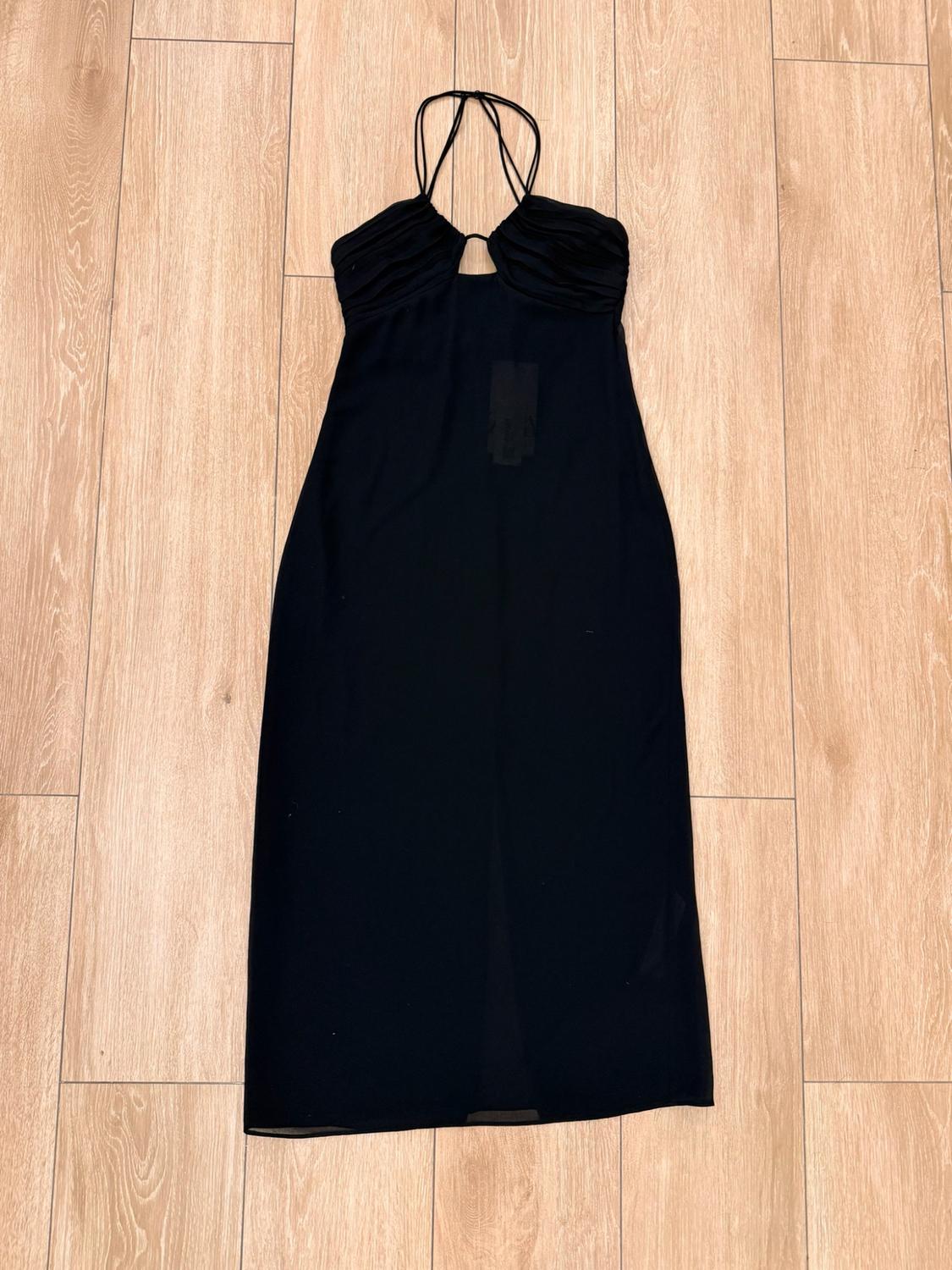 Black maxi dress with spaghetti straps, a gathered neckline and a small centre slit, laid out on a light wood floor.