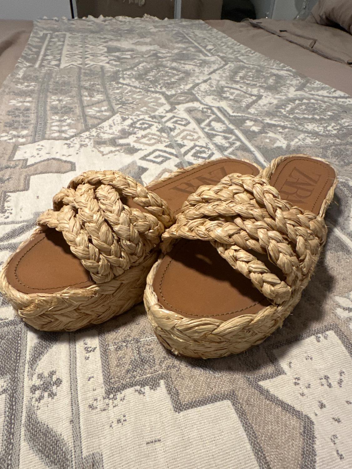 Natural coloured woven platform sandals on a blanket with a geometric design in beige and grey tones.