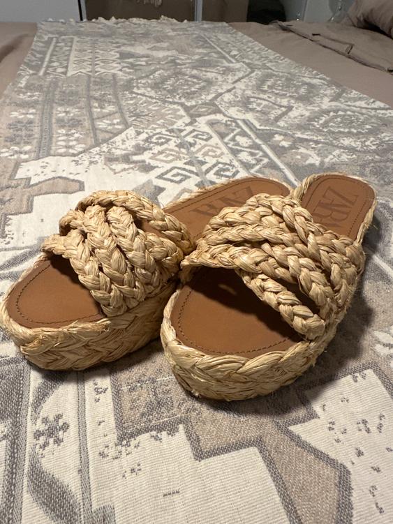 Woven platform sandals in natural color on a blanket with a geometric design in beige and gray tones.