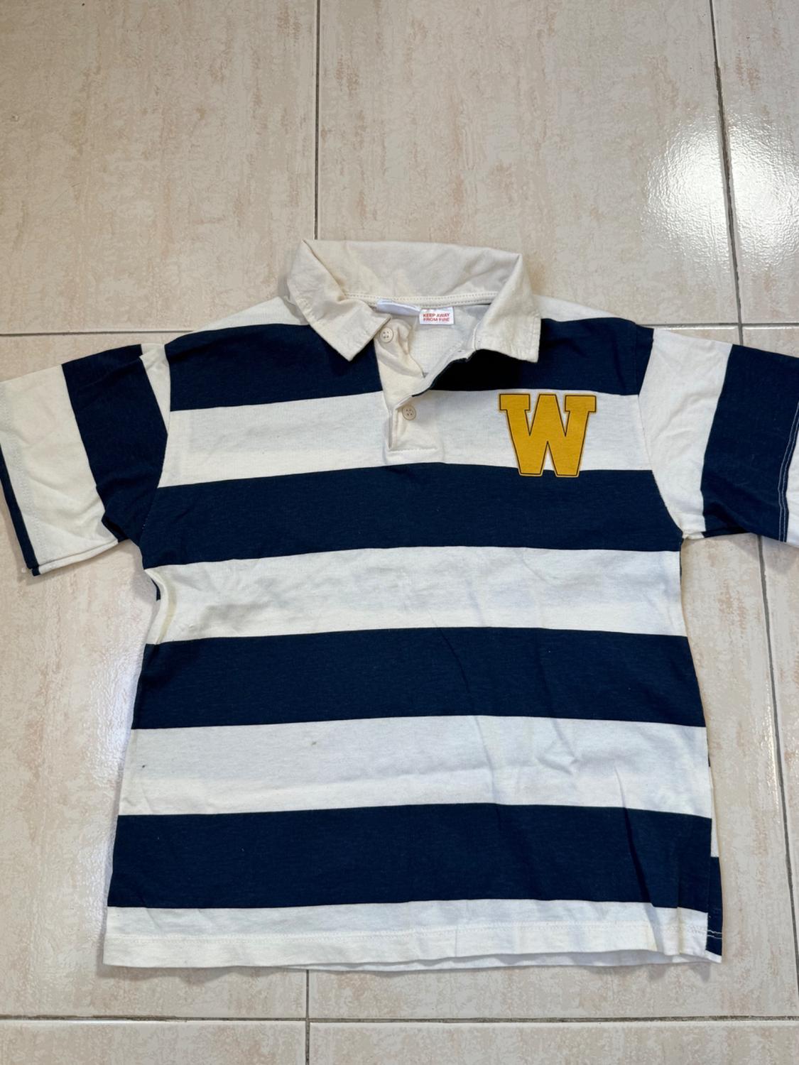 Navy and white horizontal striped polo shirt with a yellow "W" on the chest, on a light-coloured floor.