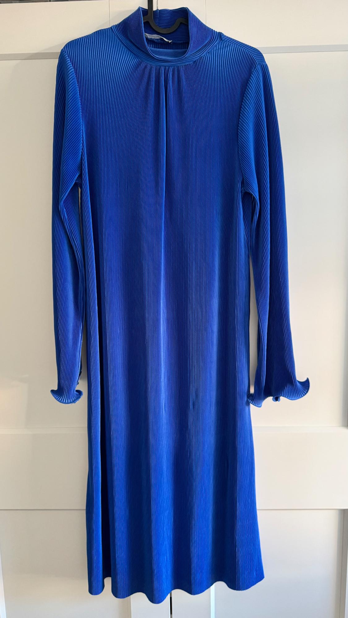 Blue long-sleeved dress with pleated texture, hanging on a hanger against a white background.