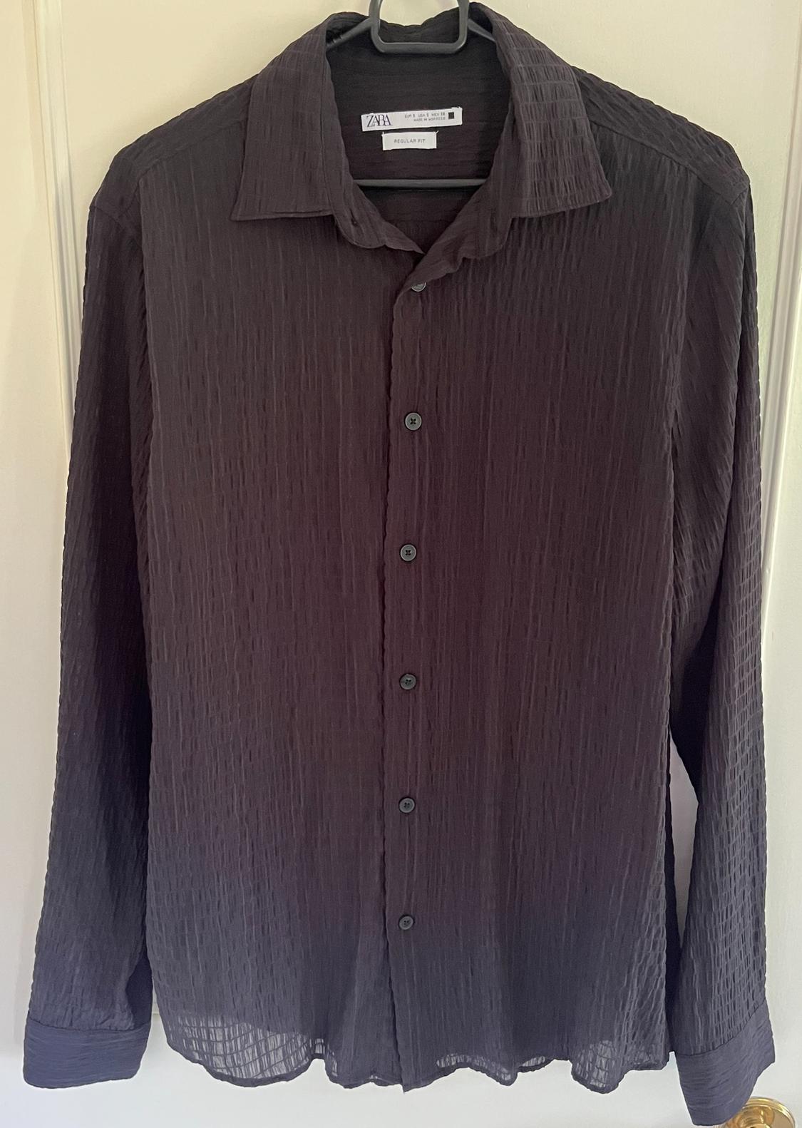 Front view of a textured black shirt with buttons and a classic collar.