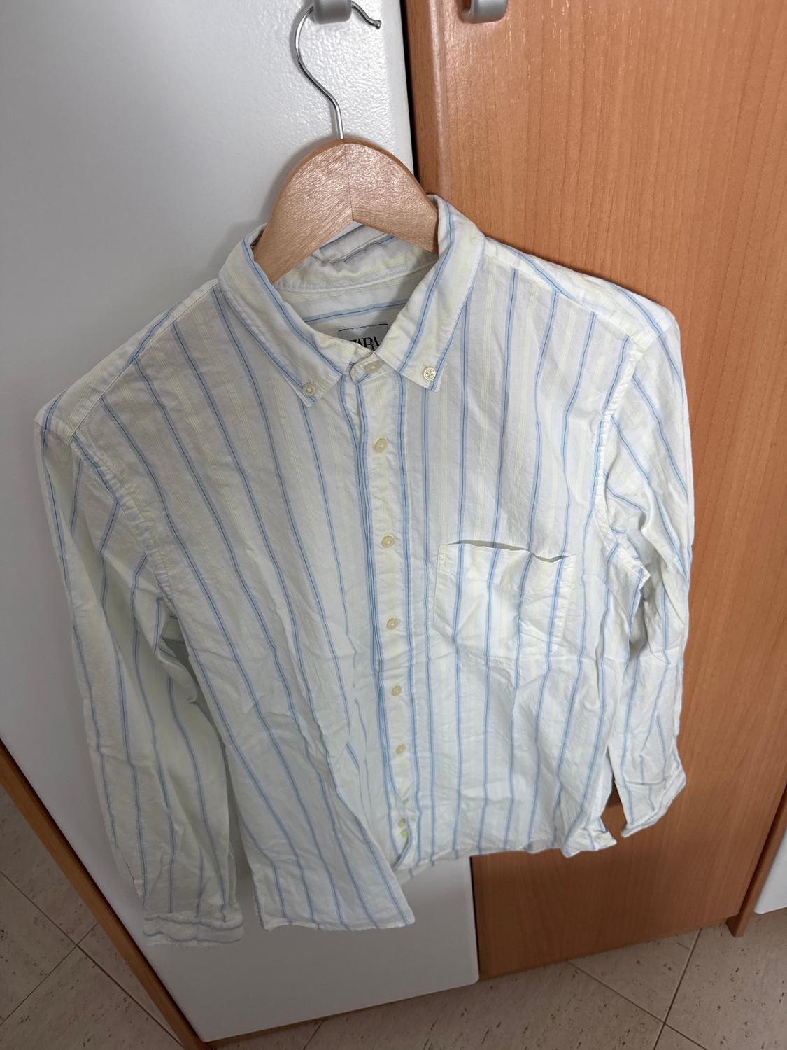 Blue and white striped shirt hanging on a wooden hanger over a light wood wardrobe door.