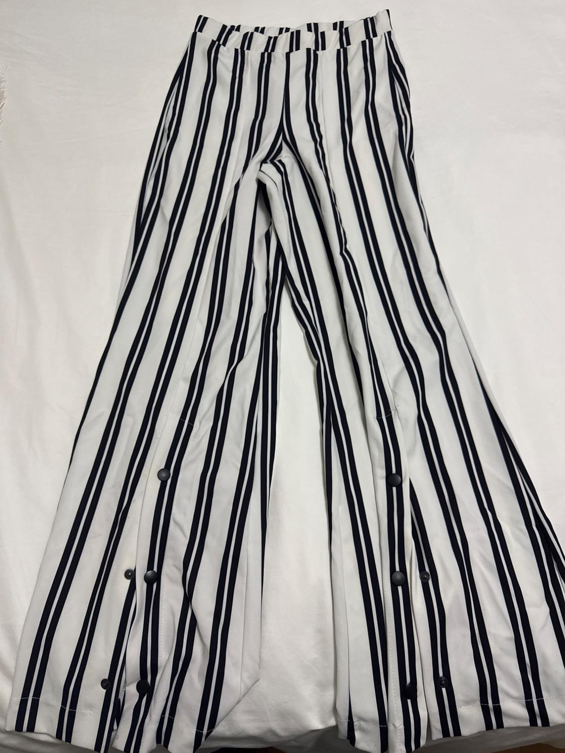 Front view of black and white vertical striped trousers with side buttons.