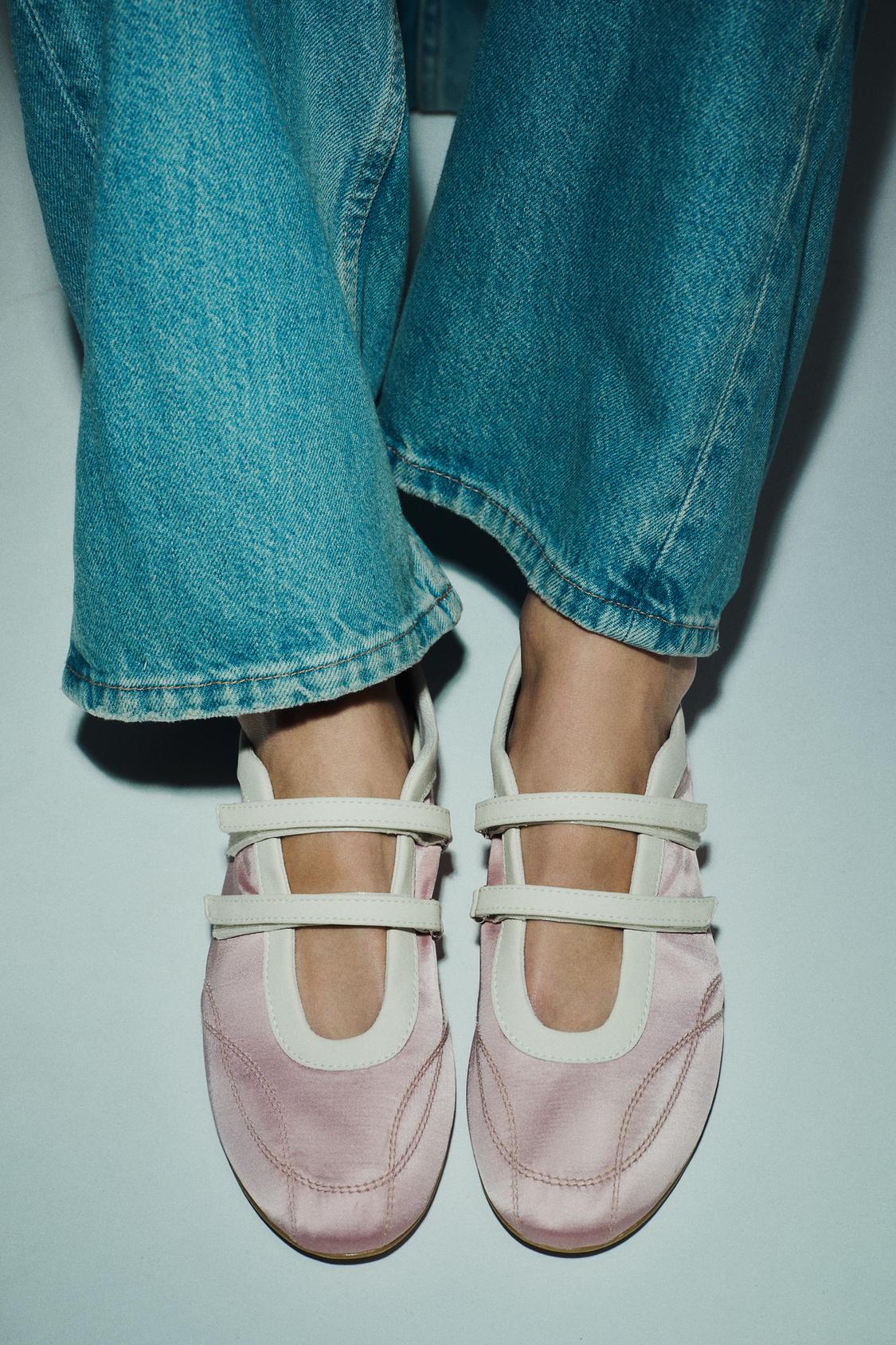 Posnetek od blizu rožnatih čevljev z belimi detajli, zasnova z dvema paščkoma in okroglo konico, kombiniranih z kavbojkami.