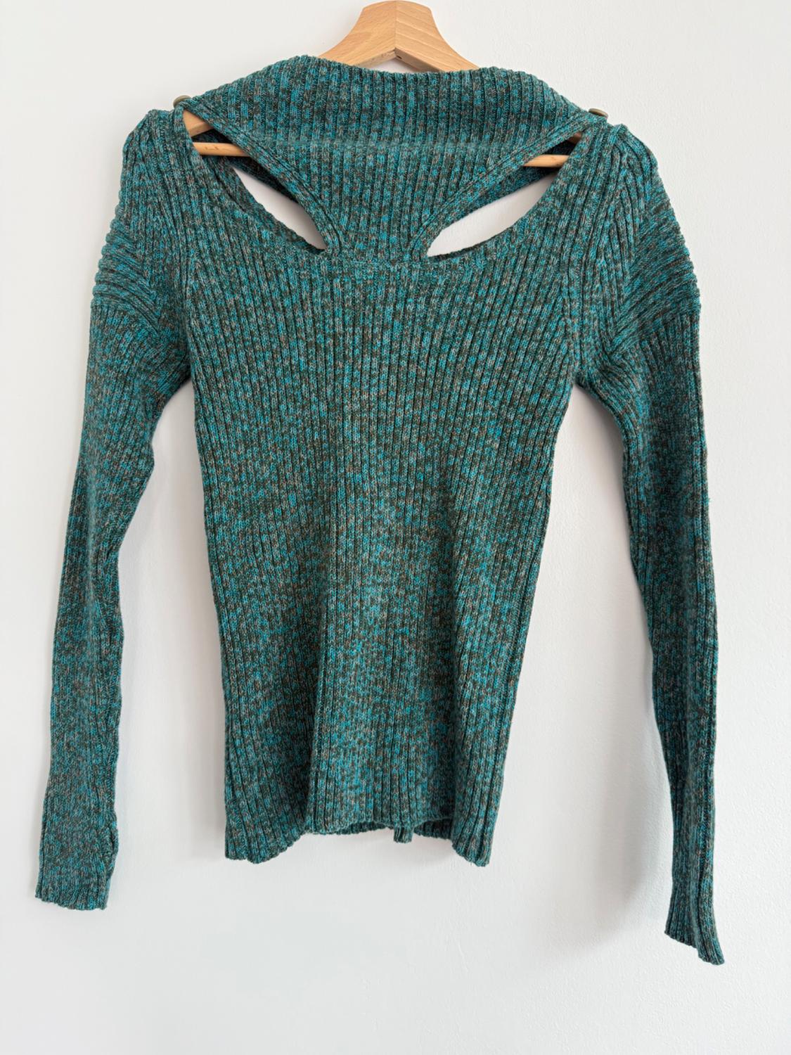 Green knitted jumper with cut-out back design, hanging on a wooden hanger against a white background.