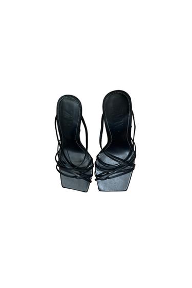 Black square-heeled sandals with thin, criss-cross straps. White background. Visible text: "ZARA" on the insole.