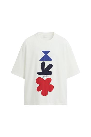 Λευκό κοντοmανίκι t-shirt με τύπωμα σχημάτων σε μπλε, μαύρο και κόκκινο χρώμα, και την επιγραφή "UNEXPECTED EXPECTATION".