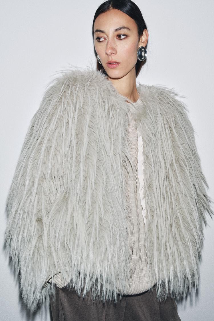 Krupni plan svijetlosive jakne s efektom krzna s dugim rukavima i kopčanjem sprijeda.