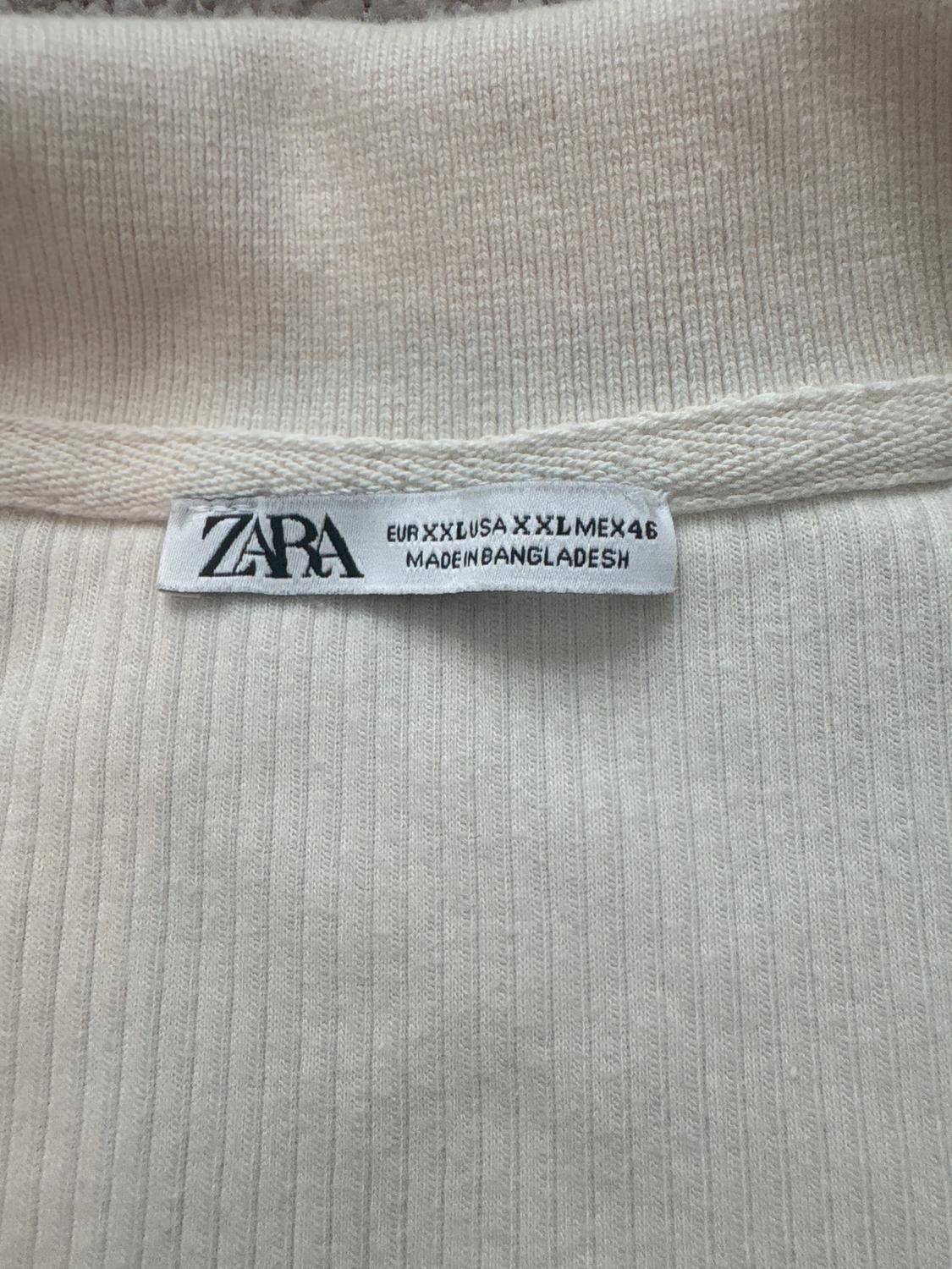 White clothing tag with text "ZARA EUR XXL USA XXL MEX 46 MADE IN BANGLADESH" on ribbed knit fabric.