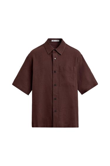 Dark brown short-sleeved shirt with a collar, front button closure, and a patch pocket on the chest against a white background.
