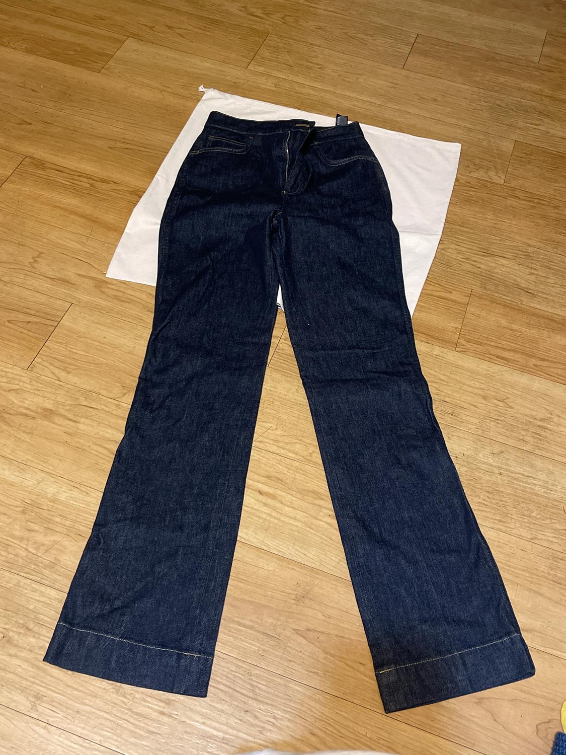 Dark wash wide-leg jeans on a light wood background and white fabric.