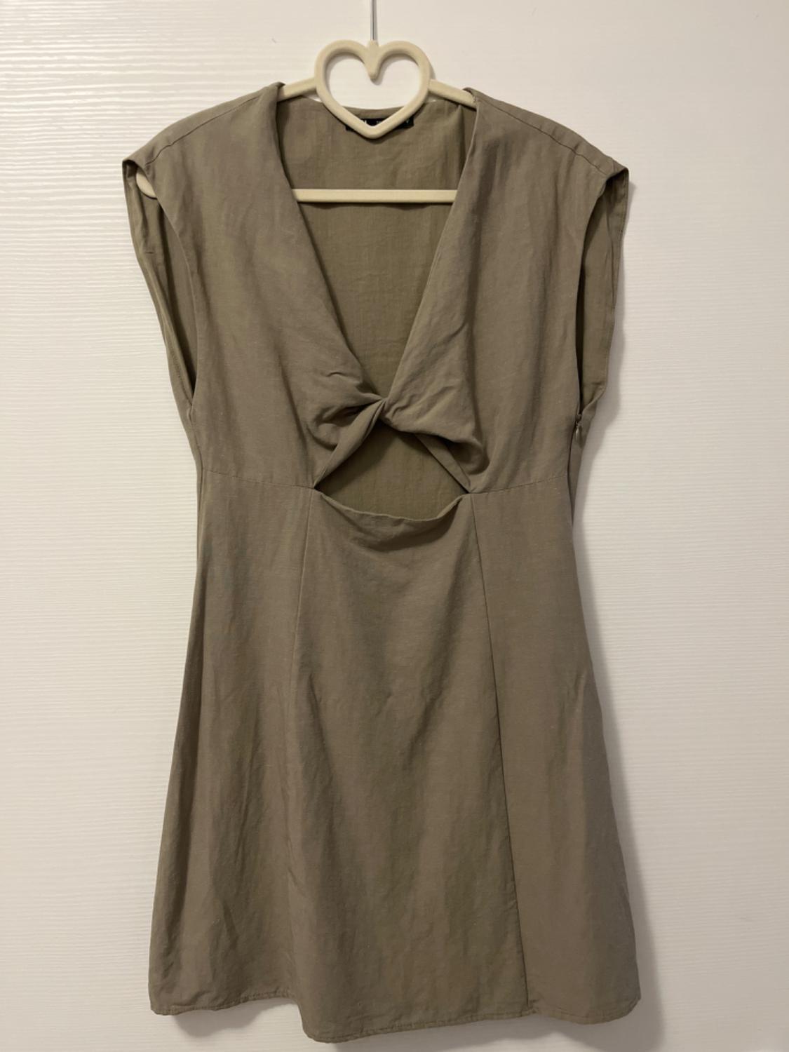 Sleeveless khaki dress with a V-neckline, front knot and waist cut-out, on a heart-shaped hanger against a white background.