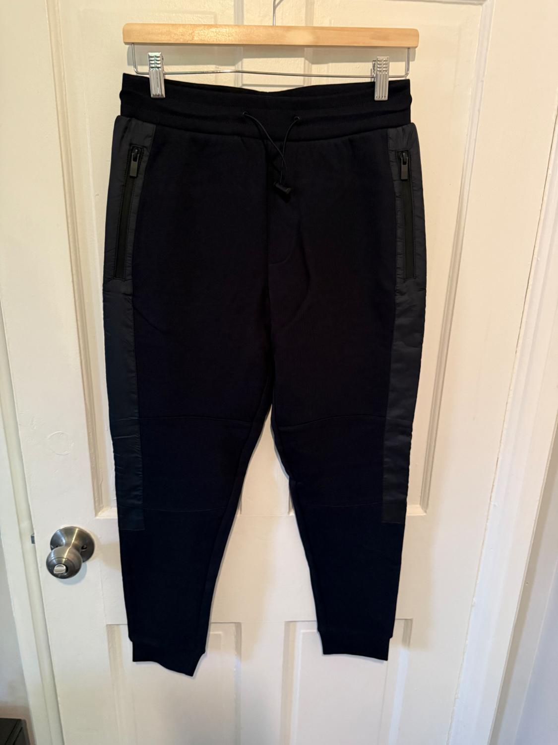 Front view of black trousers with zipped side pockets.
