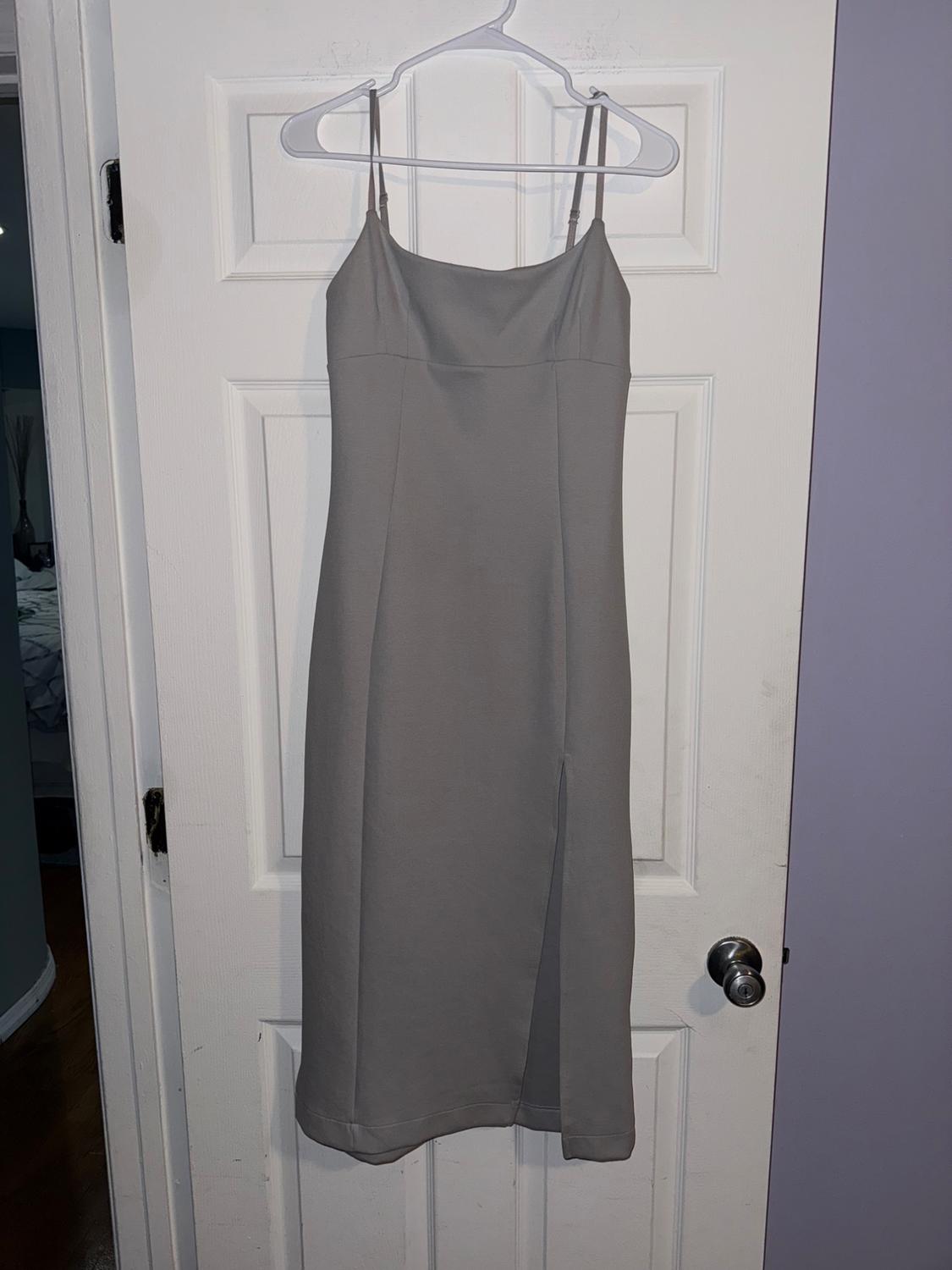 Sleeveless grey dress with thin straps, hanging on a white hanger over a white door.
