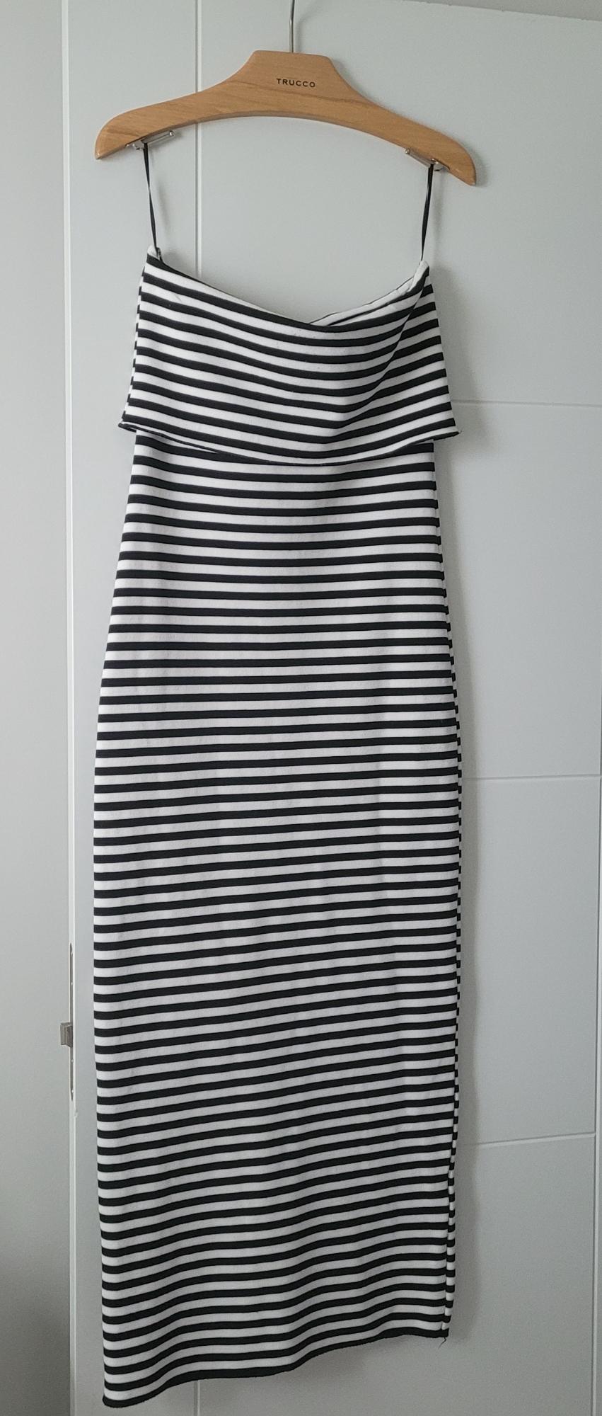 Black and white horizontal striped dress hanging on a wooden hanger with the text TRUCCO above a white door.