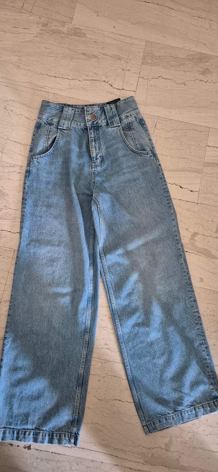 Light blue denim straight-cut jeans, placed on a beige tiled floor.
