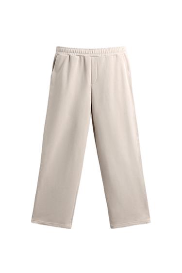 Front view of beige pants with elastic waist and side pockets.