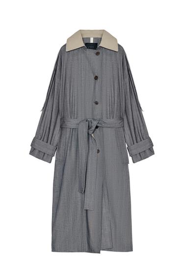 Front view of a grey trench coat with a beige lapel collar, long sleeves, front pockets and an adjustable tie belt.