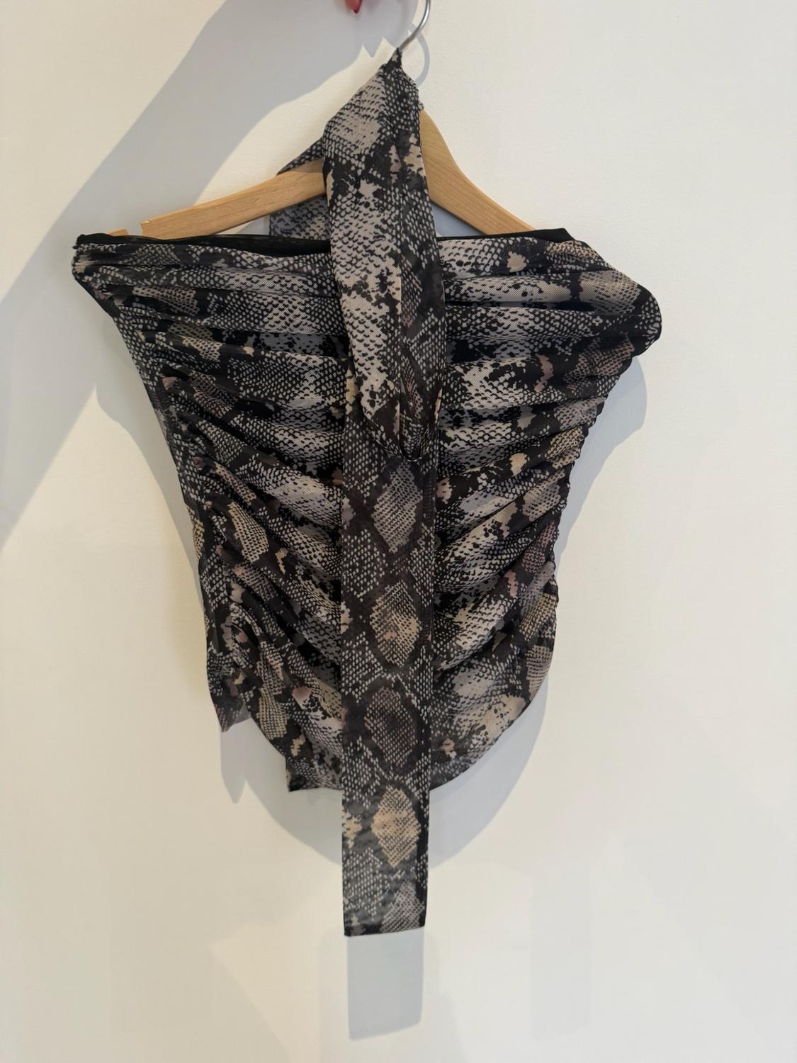Ruched top with a snake print and strap detail, hanging on a wooden hanger against a white wall.