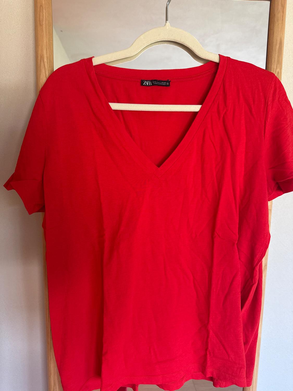 Red short-sleeved V-neck t-shirt hanging on a wooden hanger. Visible label on the collar.
