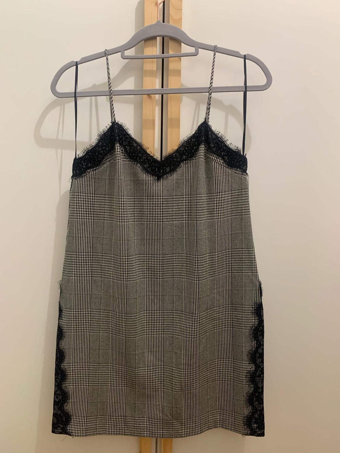 Black and white checked camisole dress with black lace details on the neckline and sides, hanging on a hanger.