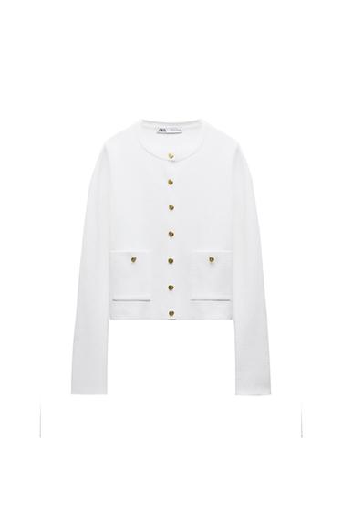 White, long-sleeved jacket with gold buttons and two front pockets. Visible label with text "ZARA WOMAN". White background.