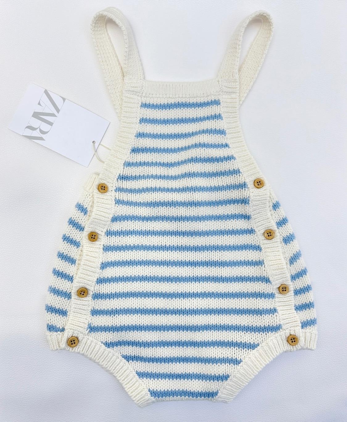 Baby's blue and white striped knitted romper, with straps and side buttons on a white background. Label with the text ZARA.