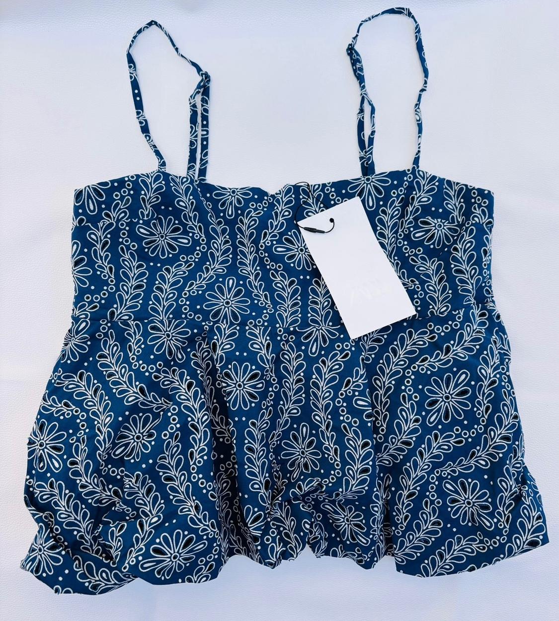 Navy blue camisole top with a white floral print and a ZARA label, laid flat on a white surface.