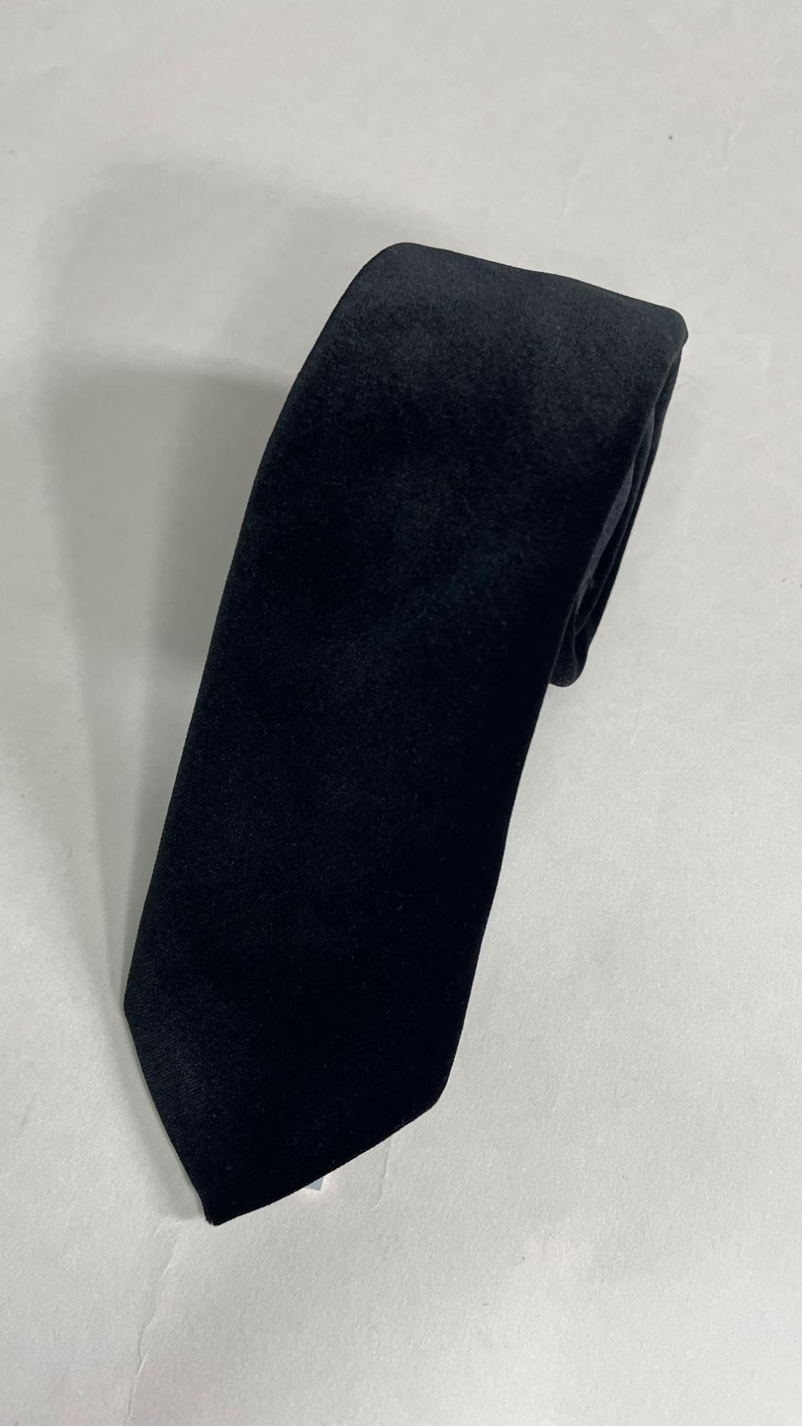 Black tie rolled up on a white background, showing soft texture and classic design.