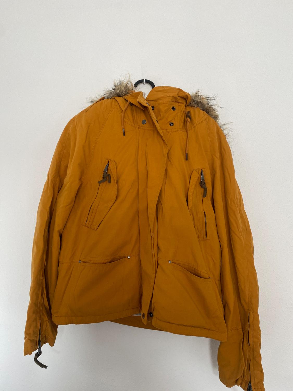 Front view of a yellow jacket with a fur-lined hood and front zip pockets.