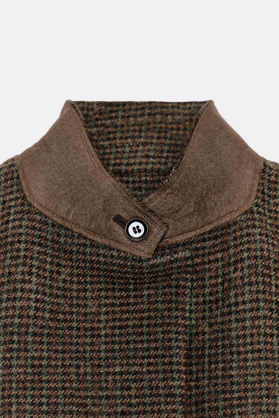 "Detail komínového límce s knoflíkem na vícebarevném saku s malými kostkami."